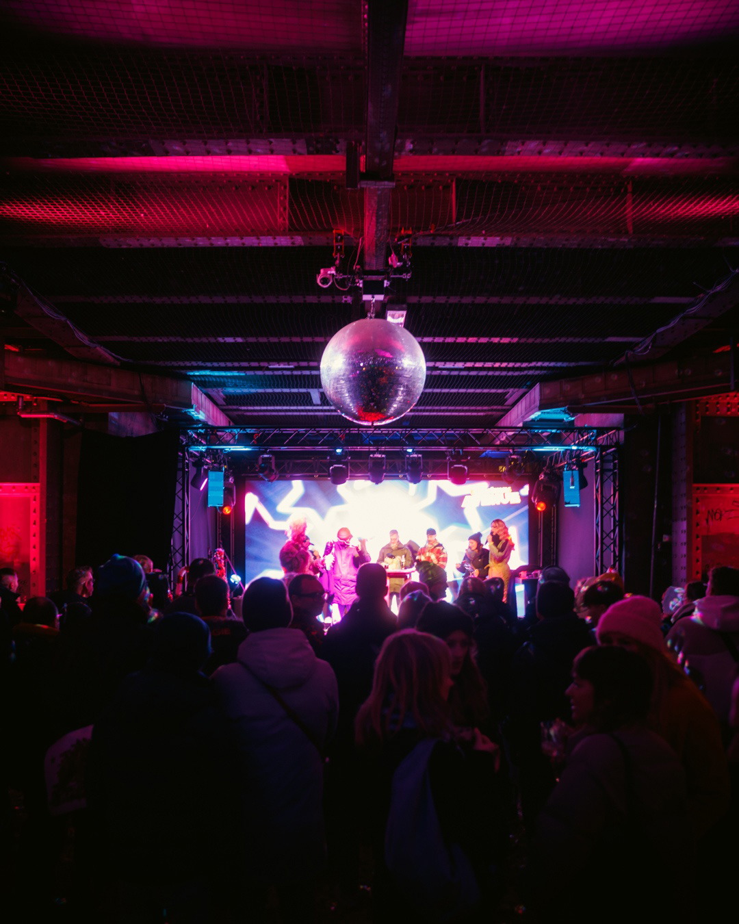 Publikum vor der bunt beleuchteten Bühne unter einer Discokugel