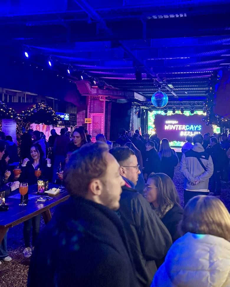 Gäste stehen bei den Winterdays Berlin in einer stimmungsvoll beleuchteten Location zusammen, trinken Cocktails und genießen die abendliche Atmosphäre.