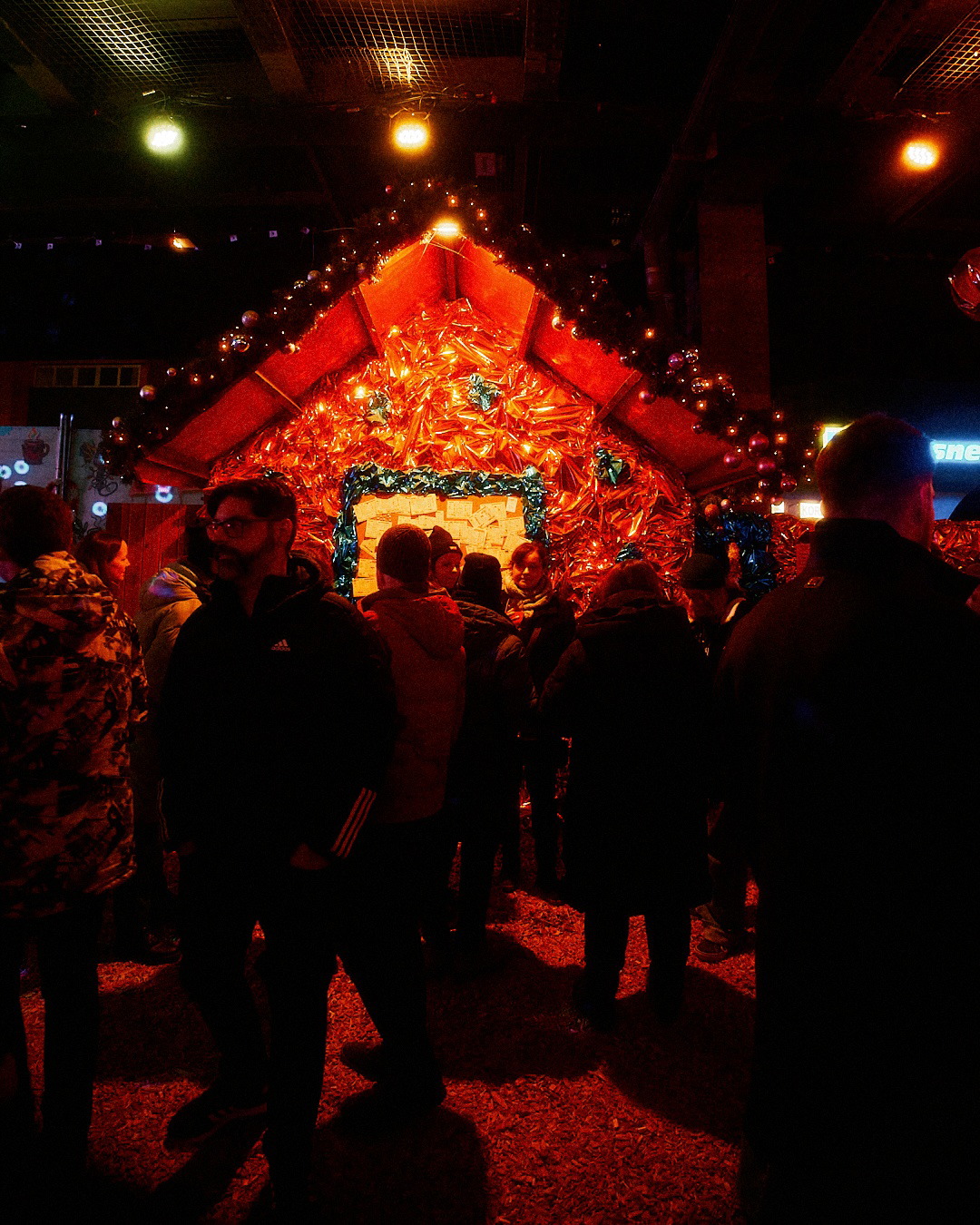 Gäste vor einer rot geschmückten Hütte auf der Christmas Avenue am Abend