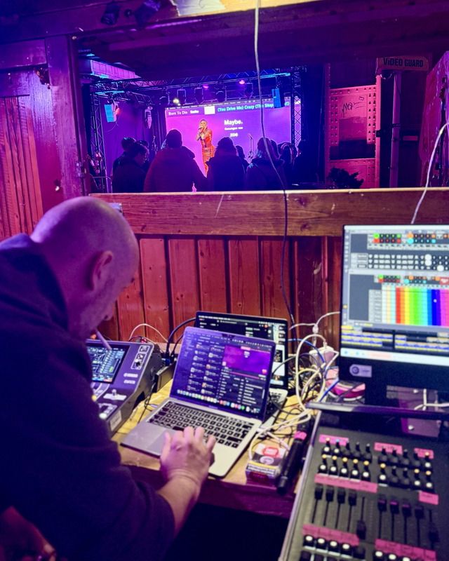 Ein Techniker bedient an einem Laptop und Mischpult die Licht- und Tontechnik während eines Karaoke-Abends in einem Club.