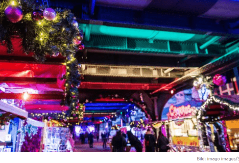 Christmas Avenue am Nollendorfplatz – LGBTQIA* Weihnachtsmarkt in Berlin Weihnachtlich geschmückte Stände unter der beleuchteten Hochbahn auf dem LGBTQIA* Weihnachtsmarkt Christmas Avenue in Berlin