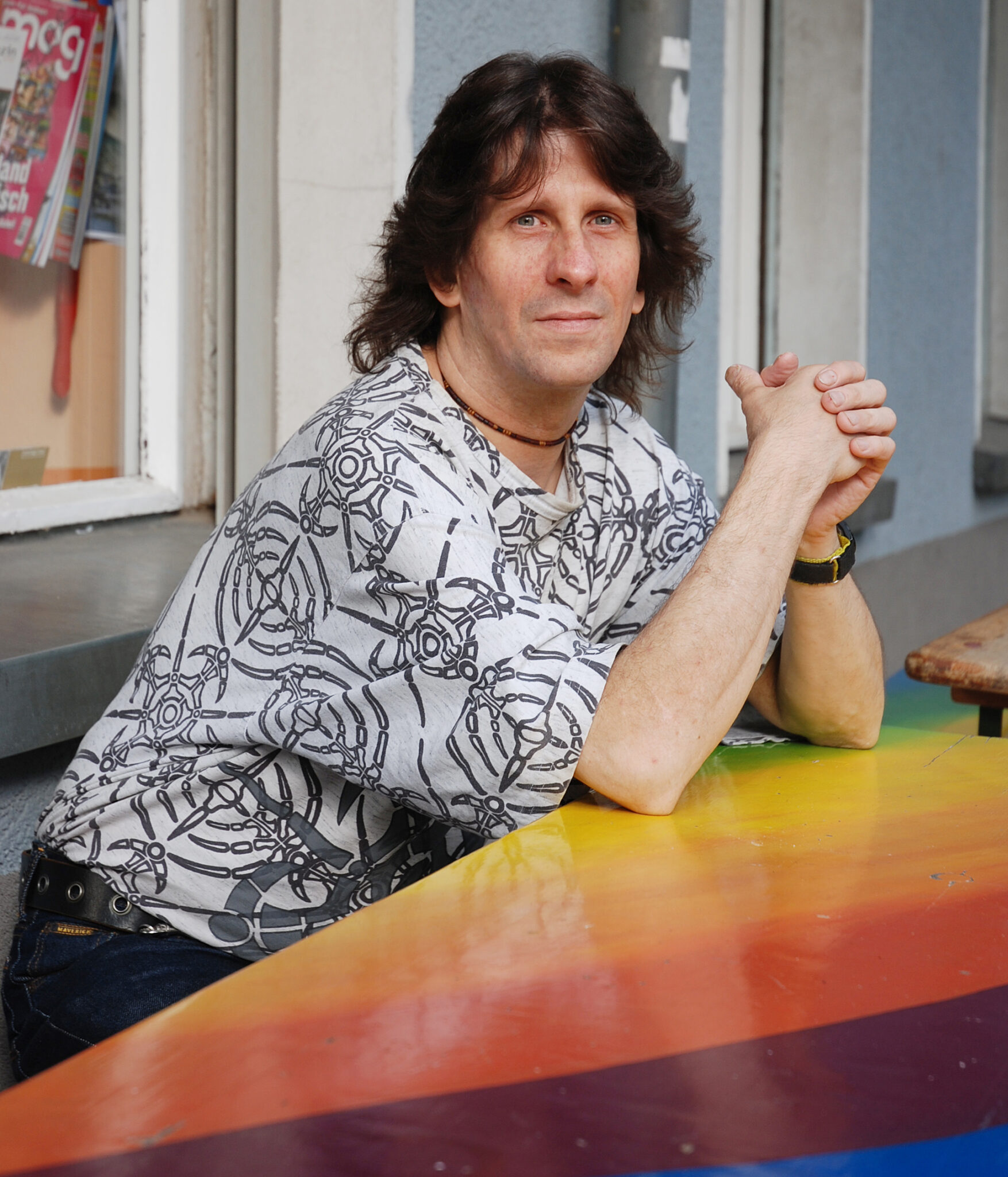 DJ Itzy sitzt an buntem Tisch draußen